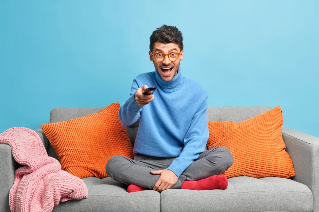 Homme enthousiaste avec télécommande prêt à regarder son abonnement IPTV avec VOD